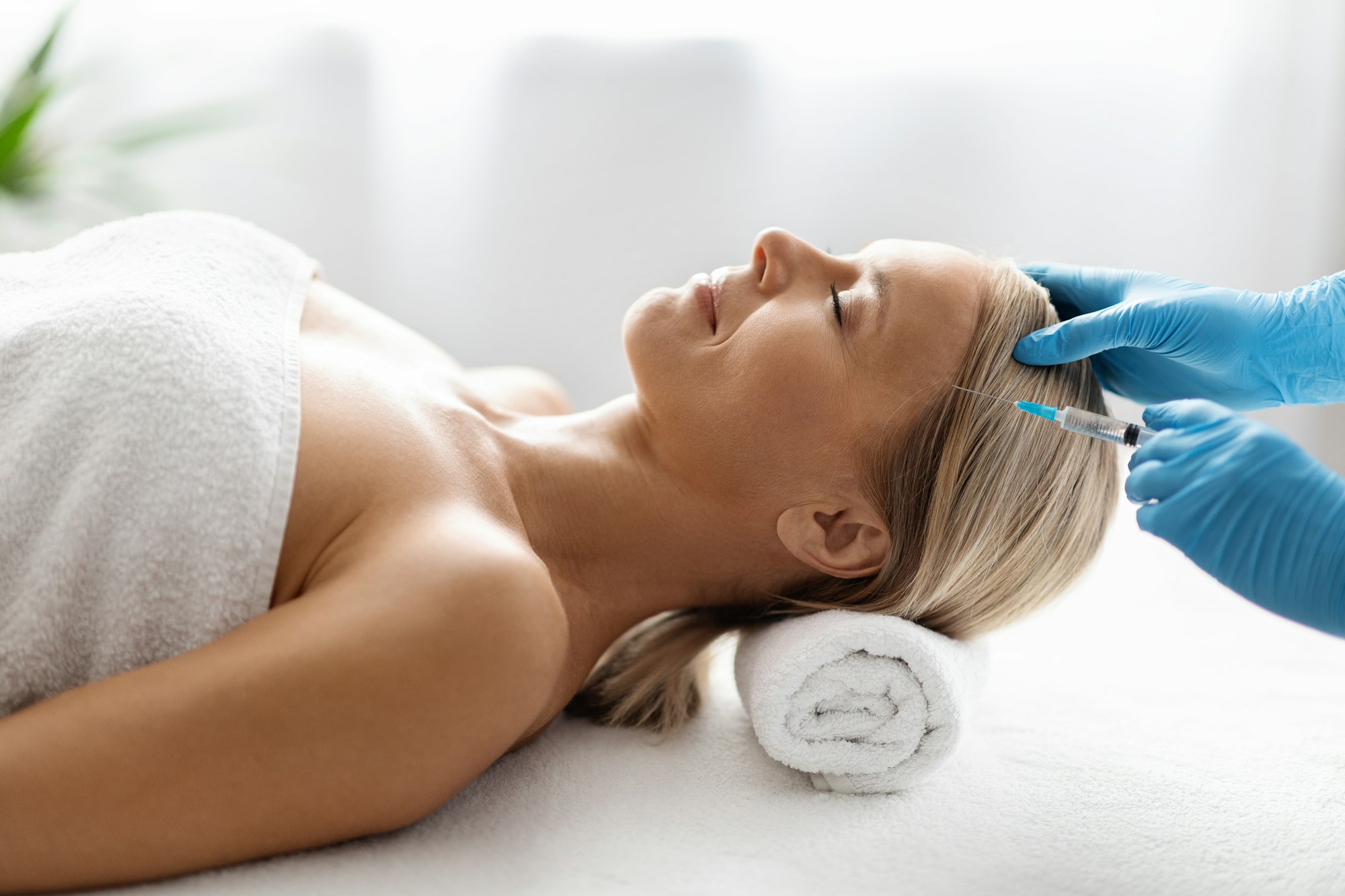 Beautiful middle aged woman getting hair treatment at beauty salon