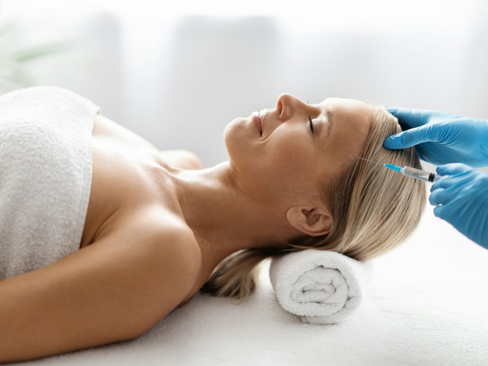 Beautiful middle aged woman getting hair treatment at beauty salon